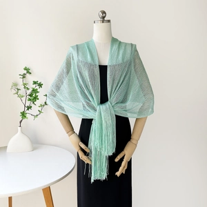Close-up of mint green knit shawl showing mesh texture and long tassel fringe detail