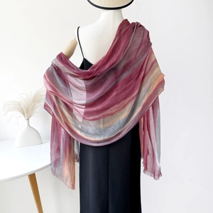 Detail of soft gradient shawl fabric showing warm tones and delicate fringe edges