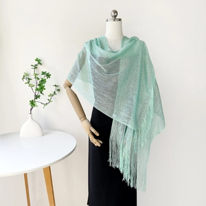 Detail of mint green tassel shawl with mesh texture on an elegant mannequin