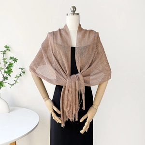 Detailed texture of hollow-out metallic gold shawl with elegant tassel fringe accents
