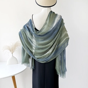 Detailed view of the green and blue gradient fabric with delicate fringe on a scarf
