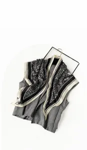 Detail eines Seidenschals mit Paisley-Muster auf grauer Weste mit Kontrastbordüre