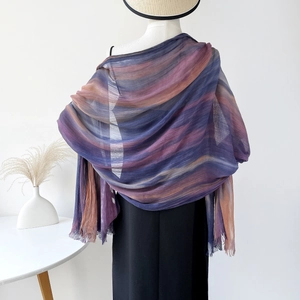 Detail of artistic gradient tassel shawl in purple and brown hanging on model