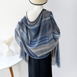 Detailed macro view of the soft blue and grey gradient striped viscose scarf with fringes