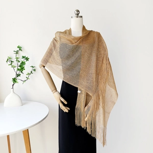 Close-up of gold metallic mesh shawl with tassel fringe and shimmering texture