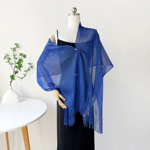 Close-up of dark blue knit shawl featuring delicate mesh weave and fringe tassels