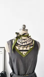 Detail view of a vintage equestrian horse pattern on a beige satin triangle neck scarf