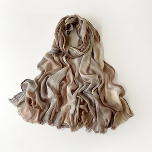 Detail of gradient pleated scarf showing fine texture and frayed edges in brown and beige