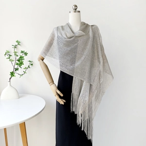 Detail of silver metallic mesh shawl featuring dense long fringe on a wooden mannequin