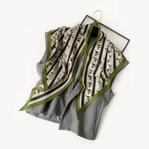 Detail of vintage beige silk scarf with green borders and black equestrian horse pattern