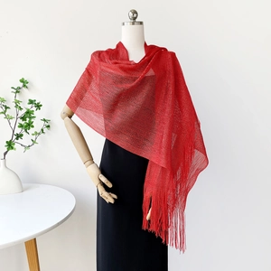 Detail of red mesh knit shawl with long fringe on a mannequin in an elegant setting