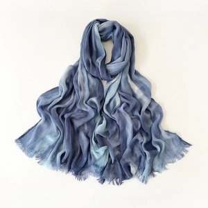 Detailed view of blue gradient tie-dye scarf fabric with elegant frayed fringe edges