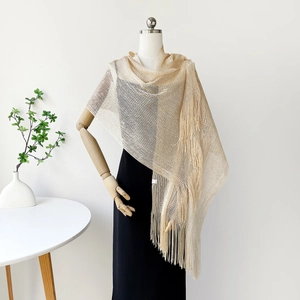 Detailed view of champagne gold shawl with metallic mesh texture and long tassel edges