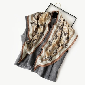 Detailed view of floral silk scarf styled on a dark gray vest against white background