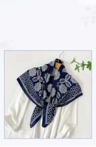 Navy blue satin scarf with white mandala pattern tied on a white collared shirt