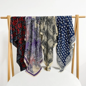 Detail shot of four lightweight scarves with paisley and floral prints on a wooden hanger