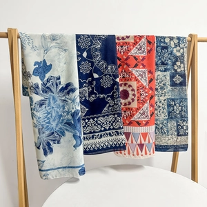 Detailed display of four paisley and floral print scarves hanging on a wooden rack