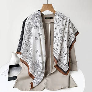 Detailed texture of paisley print silk scarf with brown border on khaki blazer