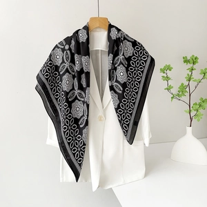 Detailed view of black and white mandala silk scarf styled on a white blazer