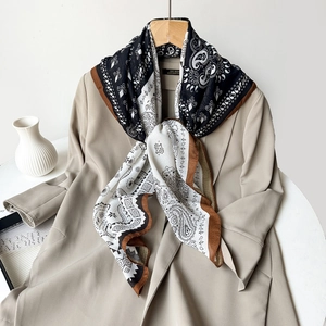 Detailed view of a vintage paisley silk scarf styled over a beige blazer for a chic look