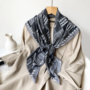 Detail of black and white geometric printed scarf paired with a beige trench coat