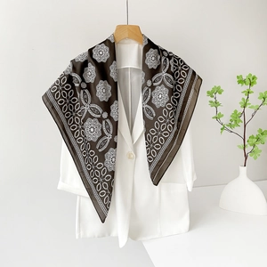 Detail of elegant dark brown silk scarf with white floral patterns on a white blazer
