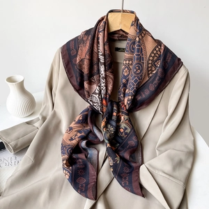 Close-up detail of paisley print silk scarf styled elegantly on a classic beige trench coat