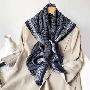 Detailed view of lightweight black and white paisley scarf on a wooden hanger with coat