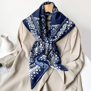 Close-up of navy blue paisley print silk scarf styled on a beige blazer jacket