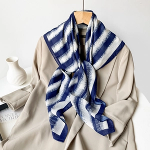 Detail of navy blue and white striped chiffon scarf styled on a beige trench coat