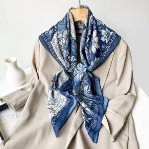 Detailed view of dark blue floral print silk scarf draped over a khaki trench coat
