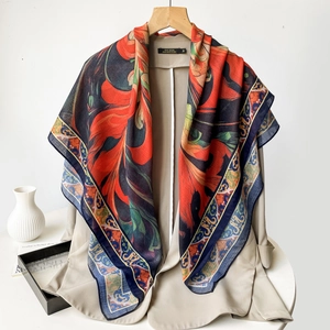 Detail of vibrant paisley printed silk scarf styled on a chic light-colored blazer