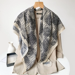 Detailed view of beige printed scarf featuring black geometric swirl patterns on linen fabric