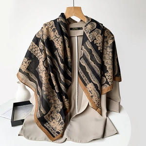 Detailed pattern of paisley printed scarf draped over a beige suit jacket for women