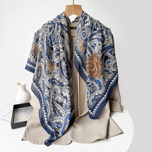 Detail of navy paisley silk scarf styled with khaki blazer on a white desk