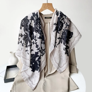 Detail of paisley floral square scarf styled over a khaki blazer on a white desk