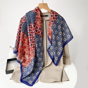 Detailed shot of lightweight paisley print silk scarf in red and blue draped on a wooden hanger