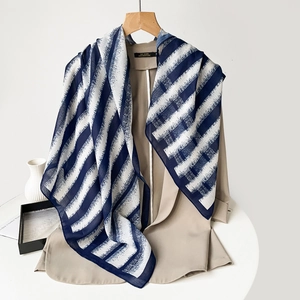 Detail of navy and white striped lightweight scarf draped over a chic beige blazer jacket