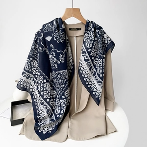 Detailed close-up of navy blue paisley floral silk scarf on a beige blazer lapel