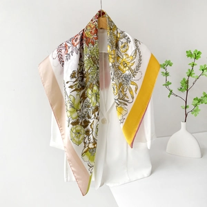Close-up of elegant floral silk scarf with pink borders draped on a white blazer