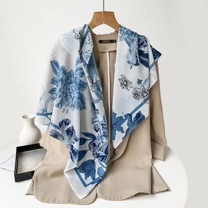 Detail of blue floral paisley square scarf styled on a chic professional suit jacket