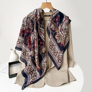 Detailed view of bohemian paisley silk scarf draped over a classic beige coat