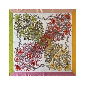 Flat lay macro shot of a 90cm square silk scarf with vibrant floral patterns and colored borders