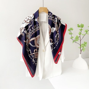 Dettaglio di un foulard quadrato in raso con stampe a catena retrò su un blazer bianco