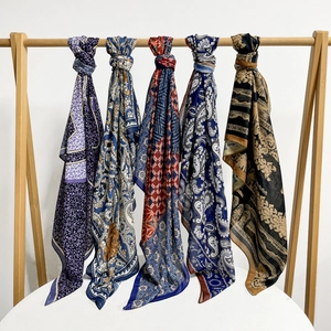 Five assorted paisley print silk scarves for women elegantly displayed on a wooden hanger