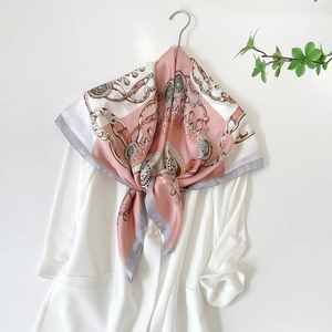 Dettaglio di un foulard in seta con stampa catena rosa e bianco su un blazer bianco