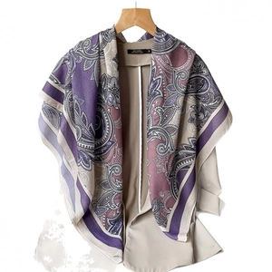 Elegant purple and beige paisley print square scarf draped on a wooden hanger with a cardigan