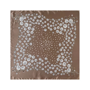 Dettaglio del foulard di seta marrone con rose bianche, pois e stampa a catena elegante