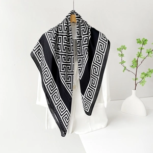 Foulard en satin à motif géométrique noir et blanc porté sur un blazer blanc chic