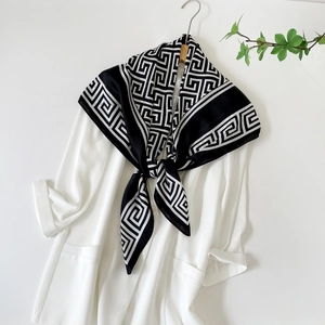 Détail d'un foulard en soie noir et blanc à motif grec sur un blazer blanc